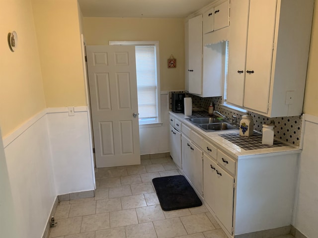 kitchen with backsplash, sink, white cabinets, and light tile patterned floors