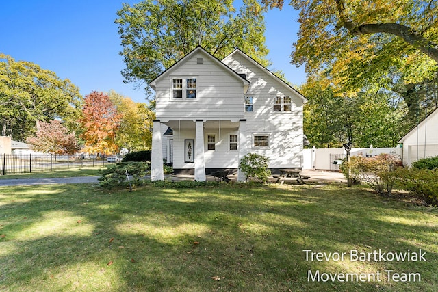 rear view of property with covered porch and a yard