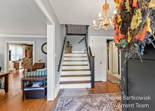 stairway with crown molding, a notable chandelier, and hardwood / wood-style flooring