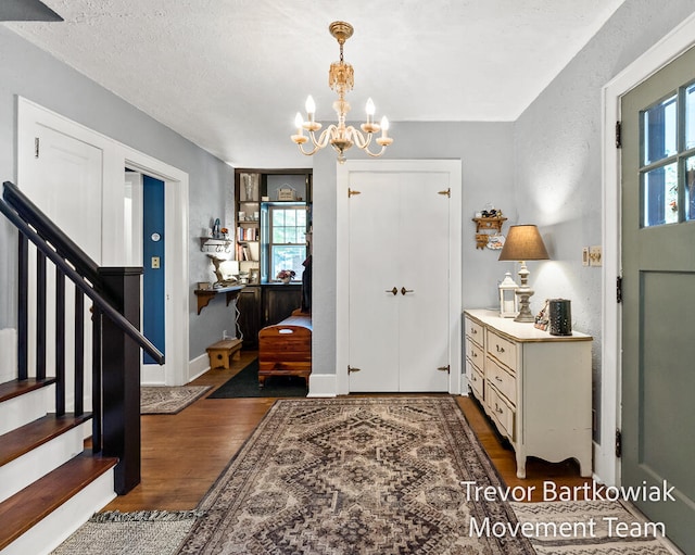 entryway with a textured ceiling, dark wood-type flooring, and a chandelier