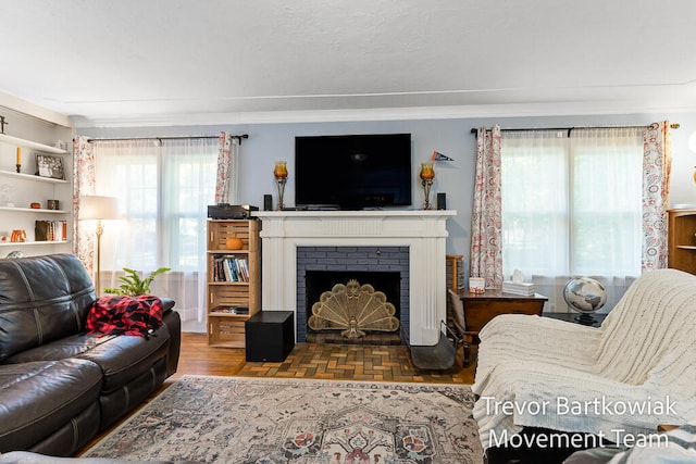 living room featuring a brick fireplace, a wealth of natural light, and crown molding