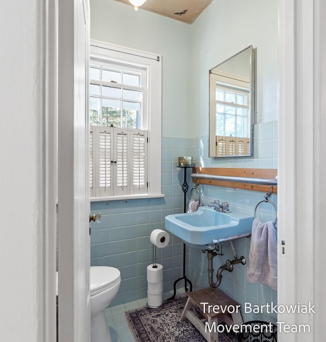 bathroom with tile patterned floors, toilet, tile walls, and sink