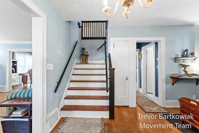 stairway with a chandelier and wood-type flooring