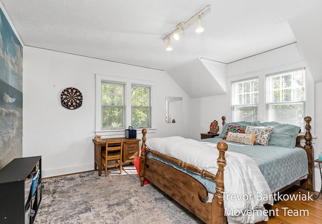 bedroom with wood-type flooring, a textured ceiling, and vaulted ceiling