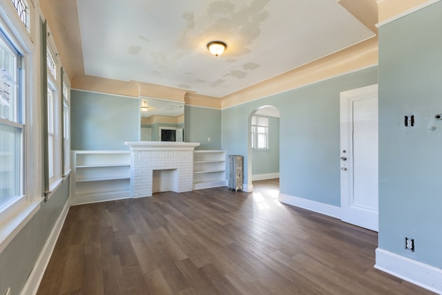 unfurnished living room featuring dark hardwood / wood-style flooring and a brick fireplace