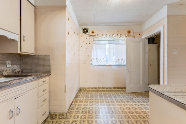 kitchen with white cabinetry and tile walls