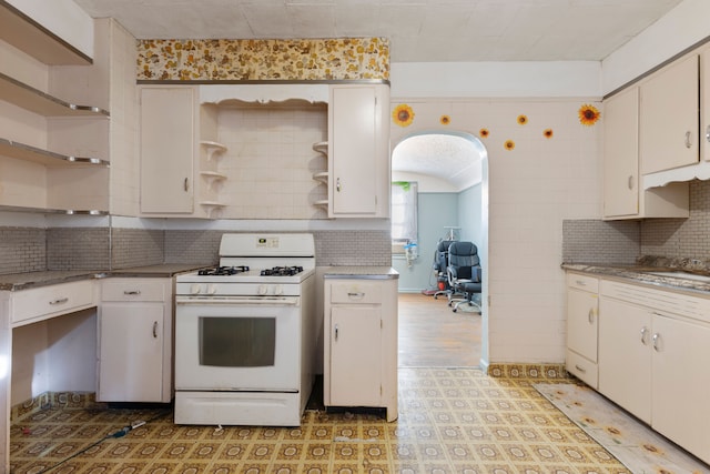 kitchen featuring tasteful backsplash, white cabinetry, and white gas stove