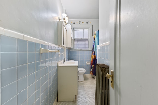 bathroom with vanity, toilet, tile walls, walk in shower, and radiator heating unit