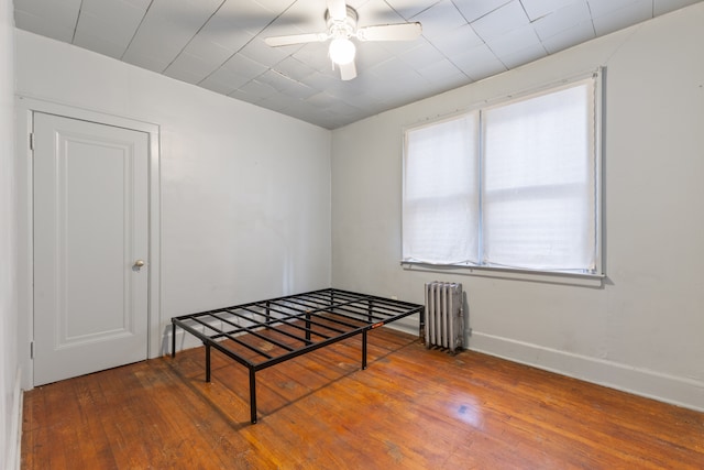 unfurnished bedroom featuring radiator heating unit, hardwood / wood-style flooring, and ceiling fan