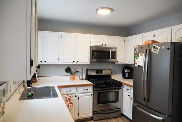 kitchen with white cabinets, wood-type flooring, stainless steel appliances, and sink