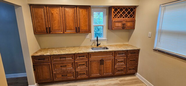 kitchen featuring light stone countertops, sink, and light wood-type flooring