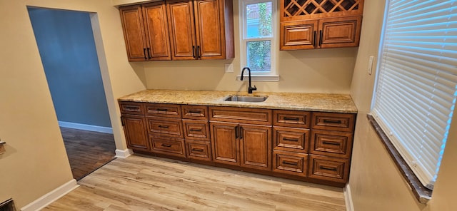 kitchen with light stone countertops, sink, and light hardwood / wood-style floors