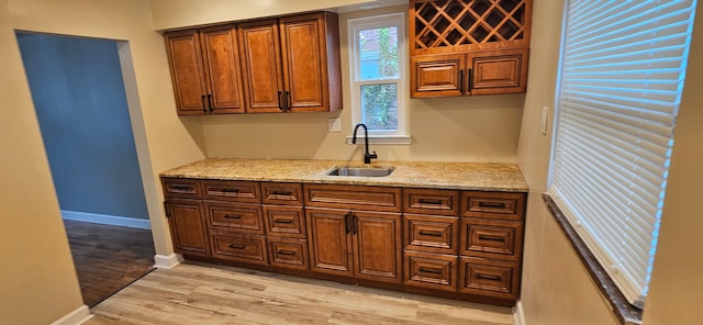 kitchen with light hardwood / wood-style floors, light stone countertops, and sink