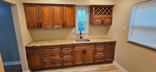 kitchen with light stone countertops, sink, and light hardwood / wood-style flooring