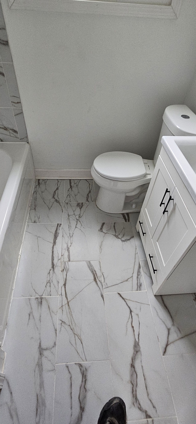 bathroom with vanity, a tub to relax in, and toilet