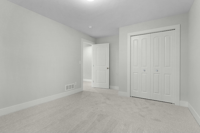 unfurnished bedroom with a closet and light colored carpet