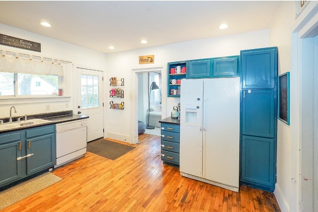 kitchen featuring blue cabinetry, light hardwood / wood-style floors, white appliances, and sink