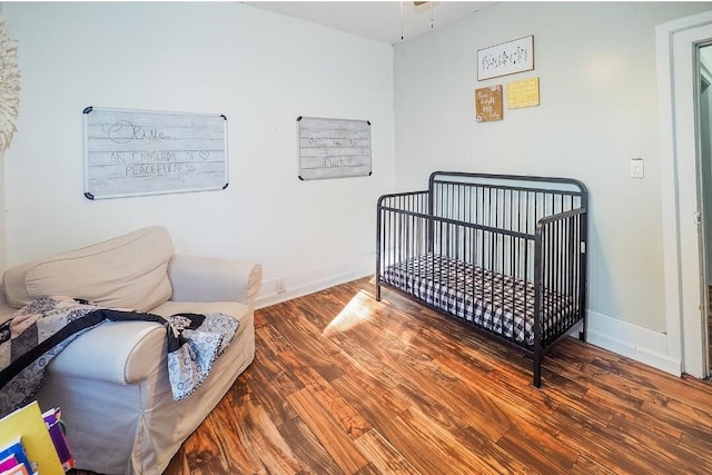 bedroom featuring a nursery area and wood-type flooring