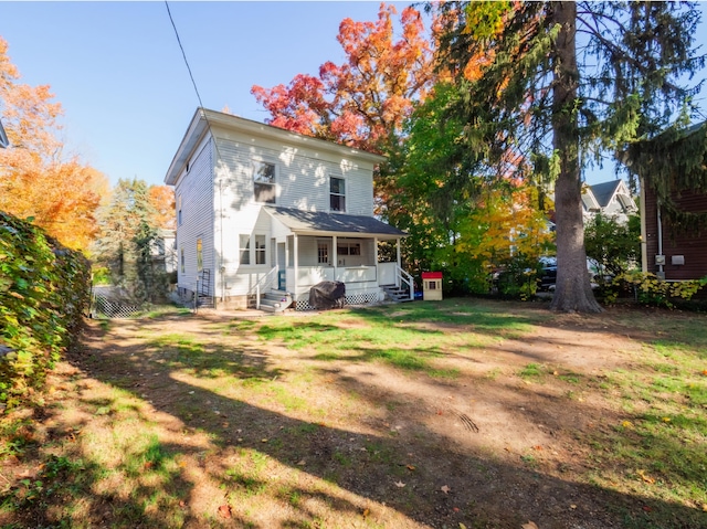 back of property featuring a porch and a yard