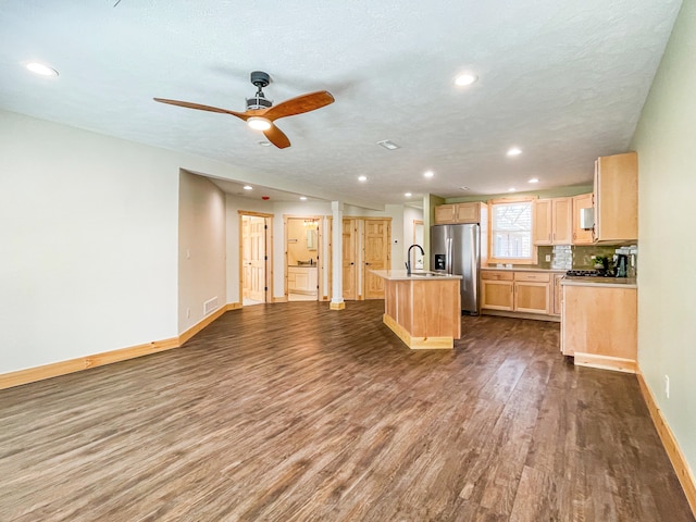 kitchen featuring light brown cabinets, dark hardwood / wood-style flooring, stainless steel refrigerator with ice dispenser, a textured ceiling, and a kitchen island with sink