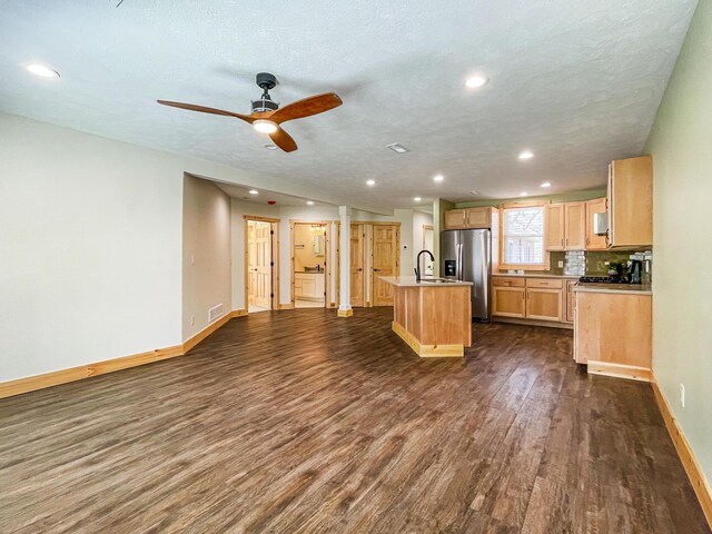 620 S Main St, Wayland, MI 49348 - kitchen featuring stainless steel fridge, dark wood-style floors, light brown cabinets, baseboards, and an island with sink