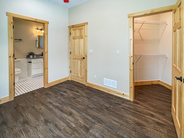 620 S Main St, Wayland, MI 49348 - unfurnished bedroom featuring dark wood-style floors, baseboards, a walk in closet, and ensuite bath