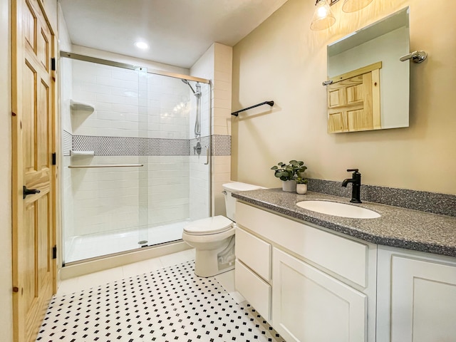 bathroom with tile patterned floors, a shower with door, vanity, and toilet