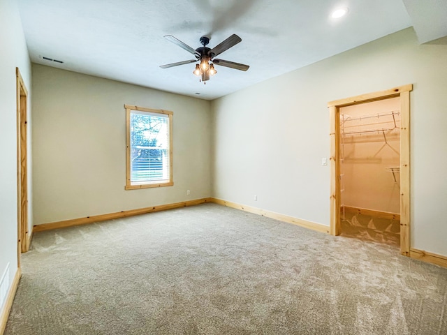 unfurnished bedroom featuring carpet, a walk in closet, a closet, and ceiling fan