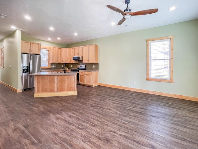 kitchen featuring appliances with stainless steel finishes, dark hardwood / wood-style flooring, light brown cabinetry, sink, and an island with sink