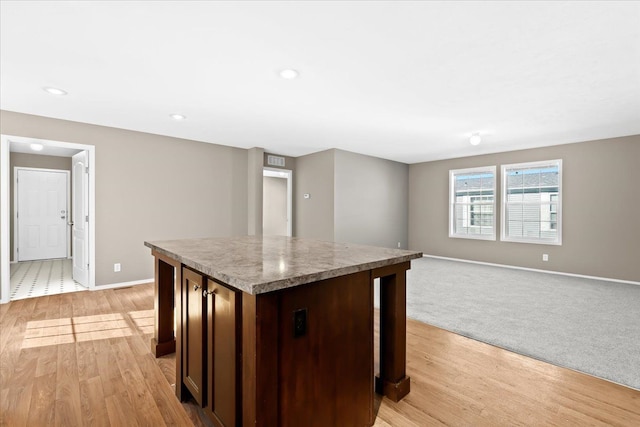 kitchen featuring a kitchen island, dark brown cabinetry, and light wood-type flooring