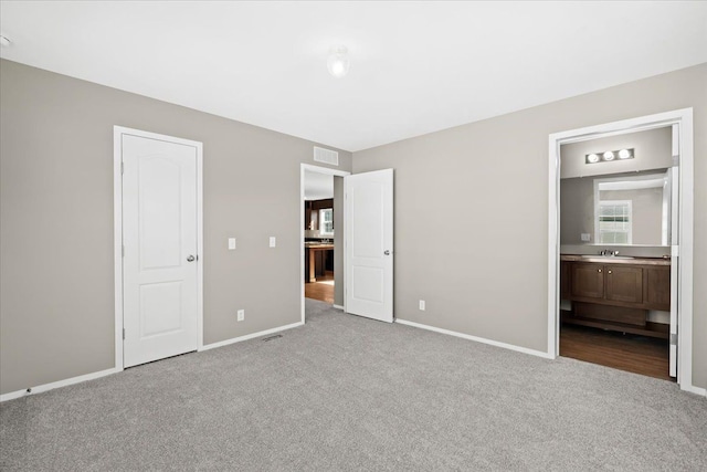 unfurnished bedroom with light colored carpet, ensuite bath, and sink