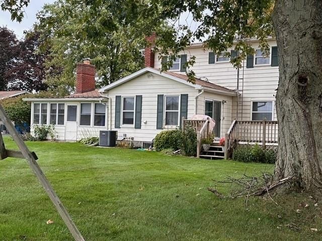 rear view of property featuring cooling unit, a yard, and a wooden deck