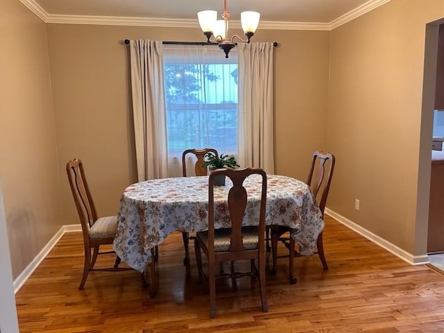 dining area with hardwood / wood-style floors, ornamental molding, and a notable chandelier