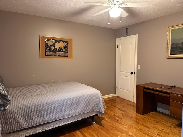 bedroom featuring ceiling fan, light hardwood / wood-style floors, and a textured ceiling