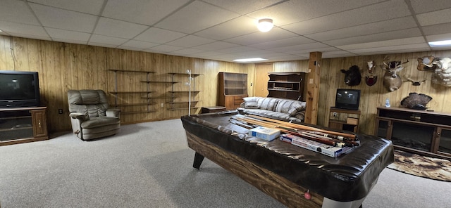 carpeted living room with wood walls, billiards, and a drop ceiling