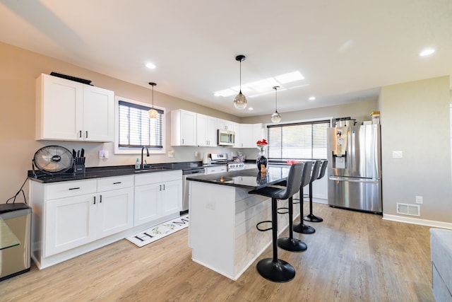 kitchen with white cabinets, plenty of natural light, a kitchen island, and appliances with stainless steel finishes