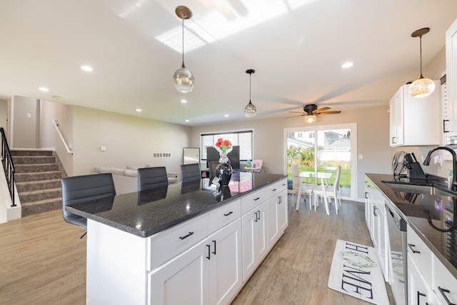 kitchen with white cabinets, light wood-type flooring, sink, and dark stone counters