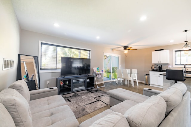 living room with light hardwood / wood-style floors, ceiling fan, and sink