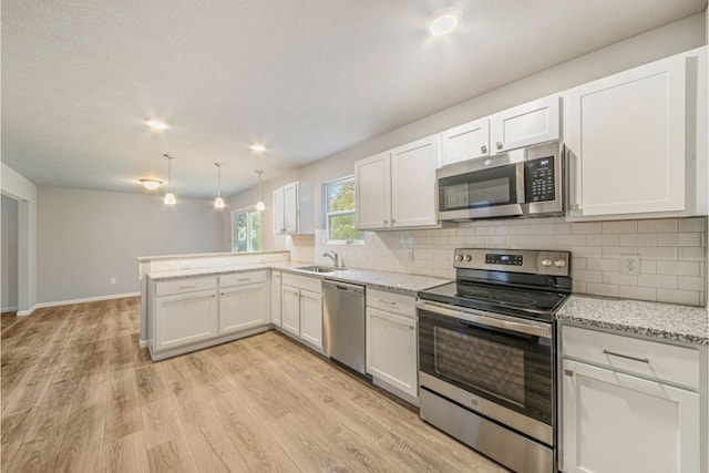 kitchen with kitchen peninsula, white cabinetry, stainless steel appliances, and light hardwood / wood-style floors