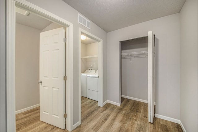 interior space with a textured ceiling, light wood-type flooring, a closet, and washing machine and clothes dryer