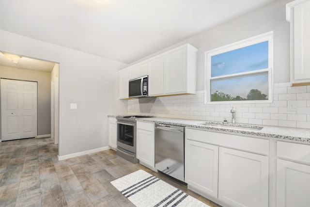 kitchen with sink, white cabinets, stainless steel appliances, and light hardwood / wood-style floors