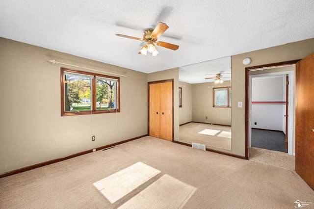 unfurnished bedroom featuring a textured ceiling, ceiling fan, and light carpet