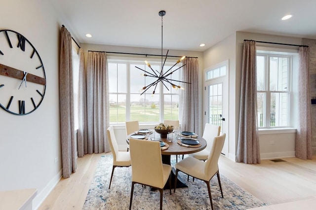 dining area featuring light hardwood / wood-style flooring, plenty of natural light, and a notable chandelier