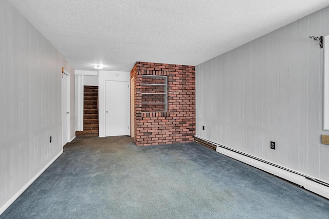 unfurnished room featuring a textured ceiling, dark carpet, baseboard heating, and brick wall