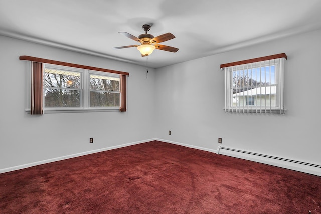 carpeted empty room featuring a wealth of natural light, ceiling fan, and a baseboard radiator