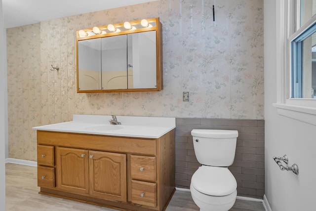 bathroom with hardwood / wood-style floors, vanity, toilet, and tile walls