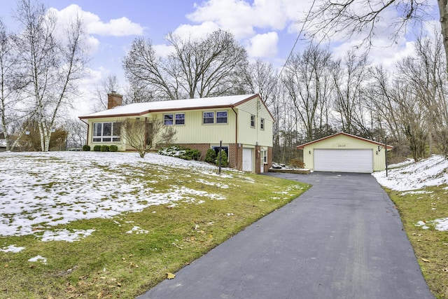 view of front facade featuring a lawn, a garage, and an outbuilding