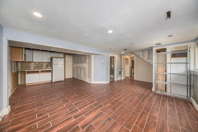 basement featuring dark hardwood / wood-style flooring, white fridge, and a textured ceiling