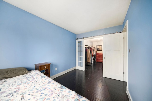 bedroom featuring dark hardwood / wood-style flooring, a walk in closet, a closet, and a barn door