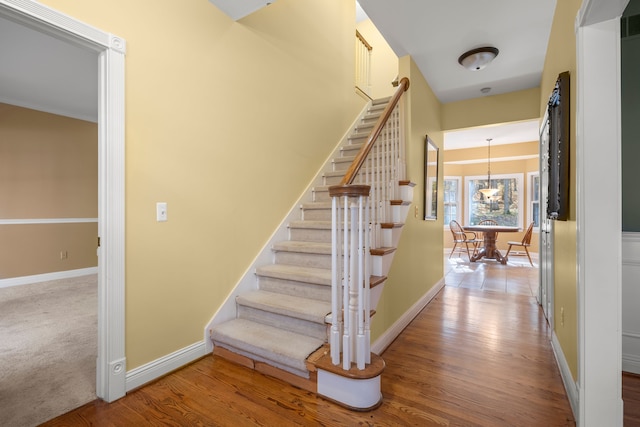 stairway featuring hardwood / wood-style floors and a notable chandelier